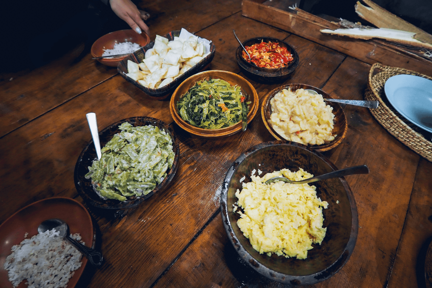 Bhutanese meal served on the floor with shared bowls of rice, vegetables, eggs, and a chili condiment